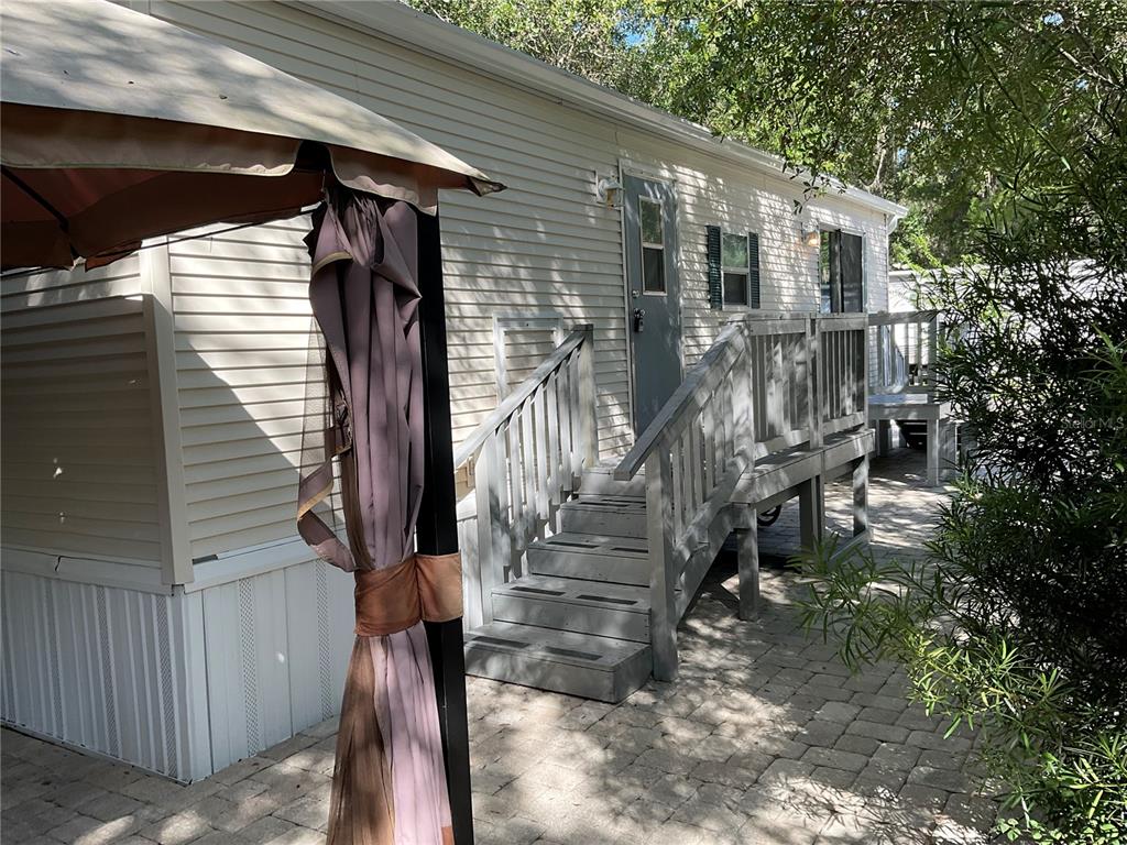 A mobile home exterior features a gray wooden staircase leading to a side entrance door — 25378 140TH STREET NE, FORT MC COY, FL