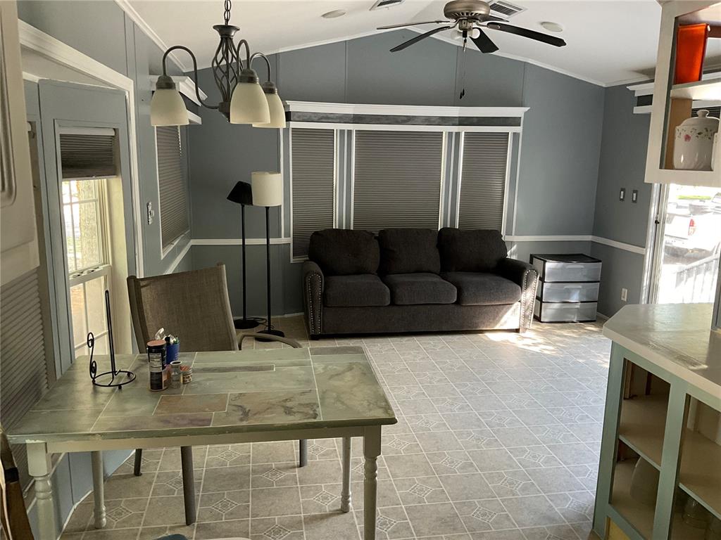 A dining area with a tiled table and a living space with a gray sofa — 25378 140TH STREET NE, FORT MC COY, FL