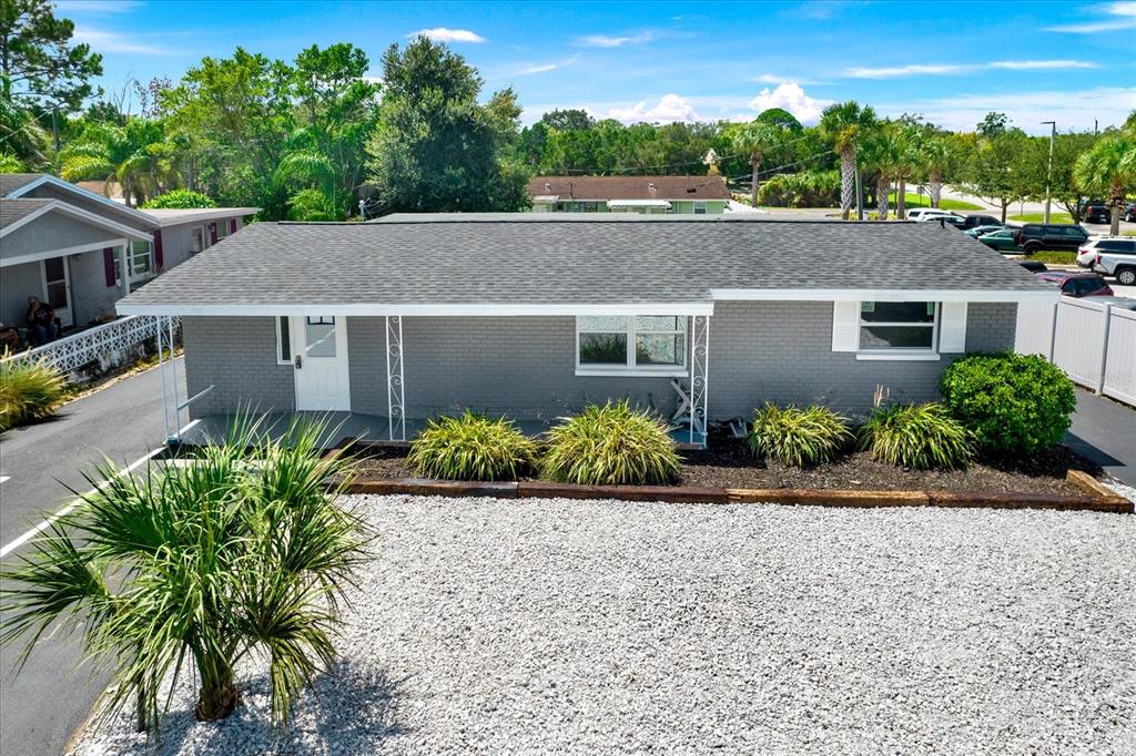 A gray, single-story house with a shingled roof and a gravel front yard — 6102 INDIANA AVENUE, NEW PORT RICHEY, FL
