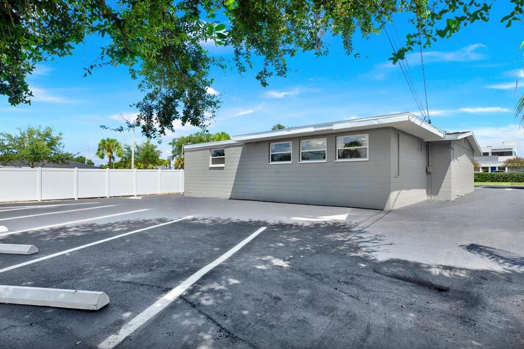 A gray, single-story commercial building stands next to an asphalt parking lot with white lines — 6102 INDIANA AVENUE, NEW PORT RICHEY, FL