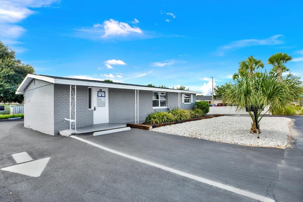A gray brick building with a white door and a gravel front yard — 6102 INDIANA AVENUE, NEW PORT RICHEY, FL