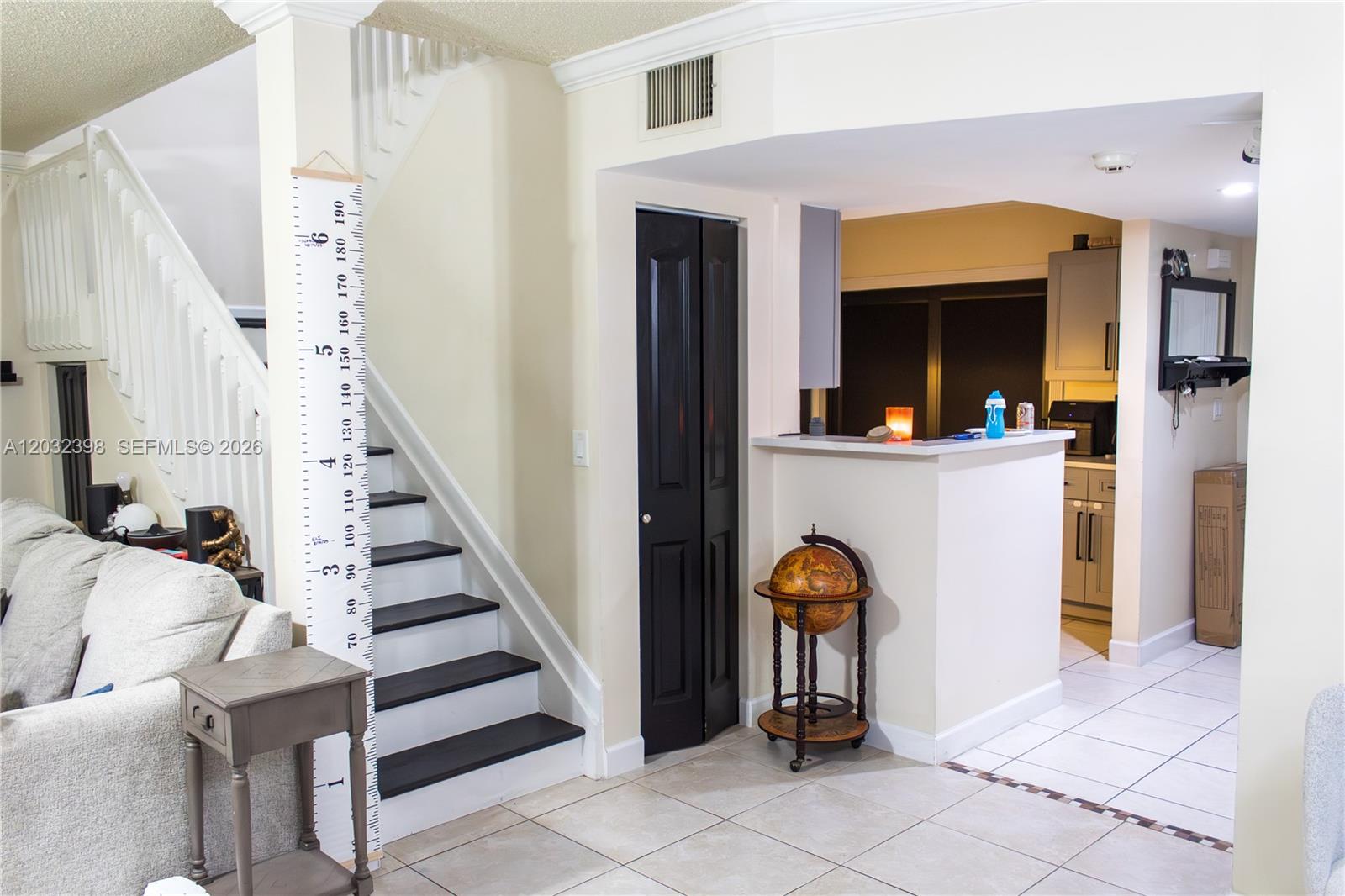 A living area features a staircase with a height chart, a black door, and a kitchen — 7645 NW 38th Ct, Sunrise FL 33351, SUNRISE, FL