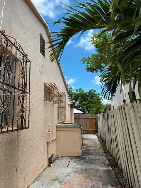 A narrow concrete walkway runs between a stucco building with decorative window grilles and a fence — 90 Flagami Blvd # 2, Miami FL 33144, MIAMI, FL