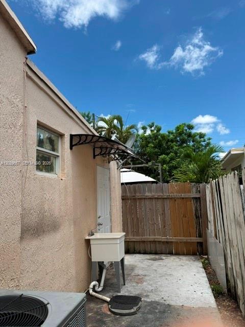 An exterior view shows a beige wall with a window, utility sink, and wooden fence — 90 Flagami Blvd # 2, Miami FL 33144, MIAMI, FL