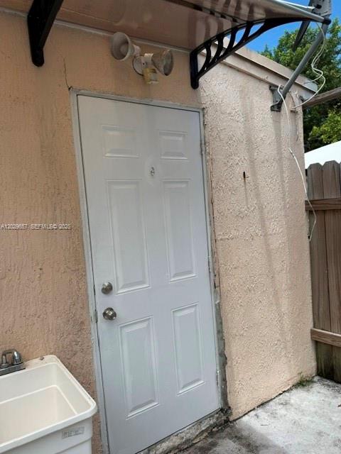 A white exterior door with a light fixture and an adjacent utility sink — 90 Flagami Blvd # 2, Miami FL 33144, MIAMI, FL