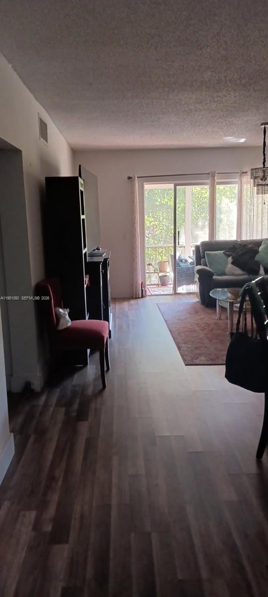 A living room features wood-look flooring, a red chair, a dark cabinet, and a sliding door — 6731 Cypress Rd # 310, Plantation FL 33317, PLANTATION, FL