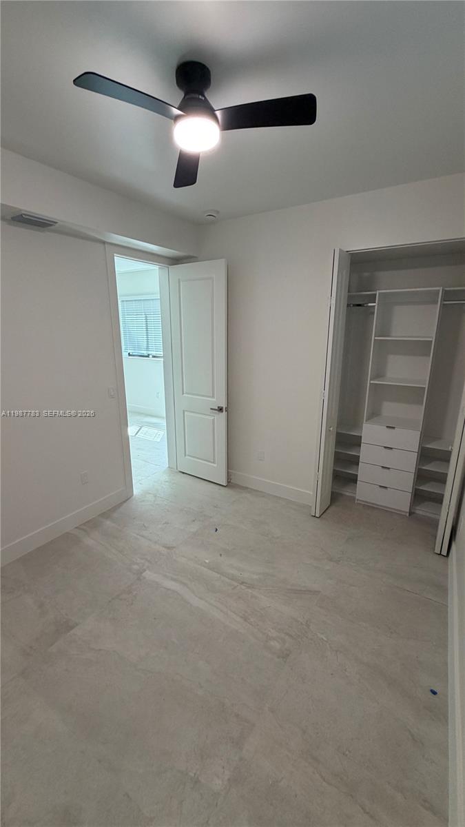 This bedroom features light-colored tile flooring, a ceiling fan, and a built-in closet system — 102 PL SW 18340, Perrine FL 33157, PERRINE, FL