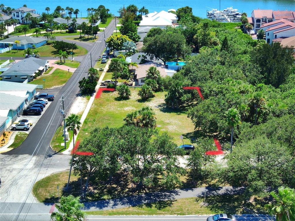 An aerial view shows a vacant, tree-covered residential lot outlined in red near a road — 102 DESOTO DRIVE, NEW SMYRNA BEACH, FL