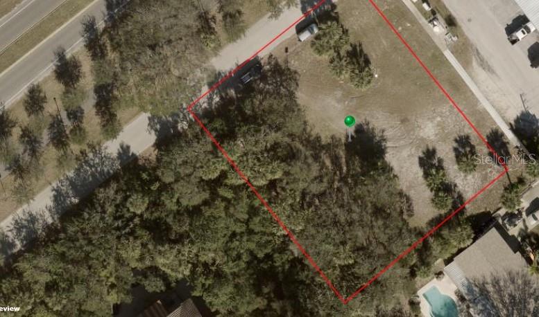 An aerial view shows a vacant, partially wooded rectangular lot outlined in red — 102 DESOTO DRIVE, NEW SMYRNA BEACH, FL