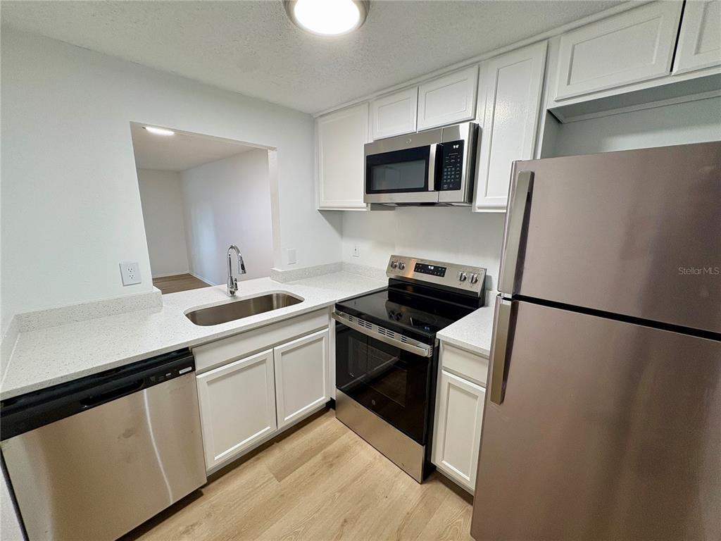A kitchen features white cabinets, stainless steel appliances, and light-colored countertops — 308 57TH AVENUE DRIVE E UNIT A, BRADENTON, FL