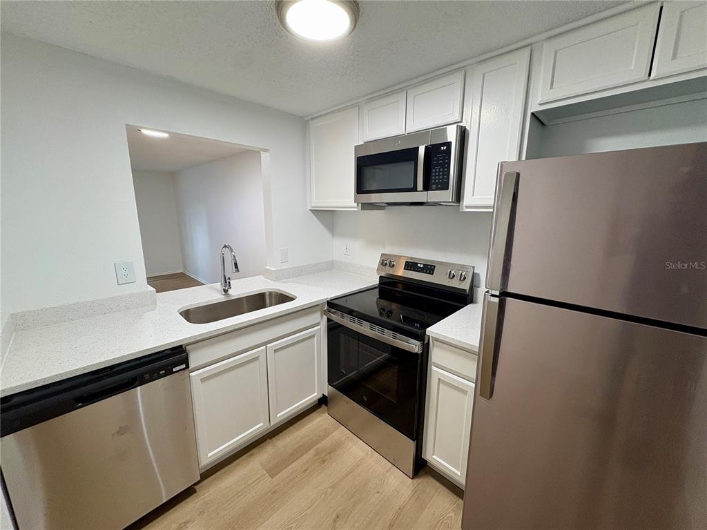 A kitchen features white cabinets, stainless steel appliances, and light-colored countertops — 308 57TH AVENUE DRIVE E UNIT A, BRADENTON, FL