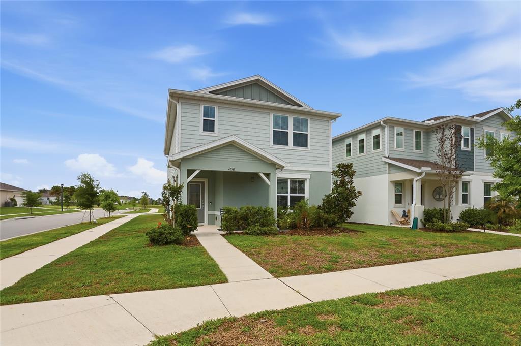 A two-story house with light green siding and a covered front porch sits on a lawn — 1818 GROVELINE ROAD, ST CLOUD, FL