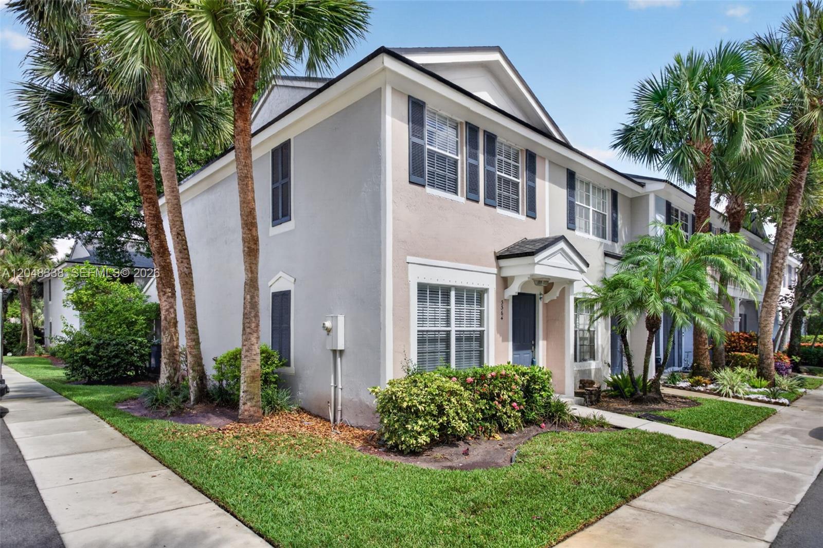 A two-story townhouse with light-colored stucco walls, dark shutters, and palm trees in the yard — 3364 Celebration Ln # 156, Margate FL 33063, MARGATE, FL