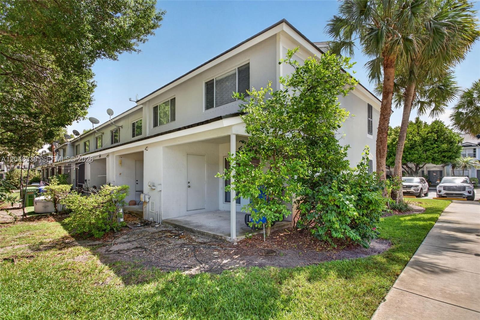 A two-story townhouse exterior features a covered concrete patio, a small tree, and landscaping — 3364 Celebration Ln # 156, Margate FL 33063, MARGATE, FL