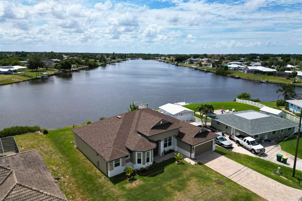 An aerial view shows a single-story house with a brown roof beside a canal — 729 CRESTVIEW CIRCLE NW, PORT CHARLOTTE, FL
