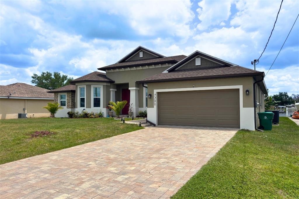 A single-story house with a paved driveway, a two-car garage, and a red front door — 729 CRESTVIEW CIRCLE NW, PORT CHARLOTTE, FL