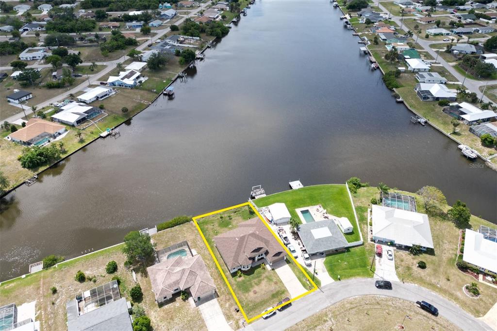 An aerial view shows a waterfront house with a yellow outline on a canal — 729 CRESTVIEW CIRCLE NW, PORT CHARLOTTE, FL