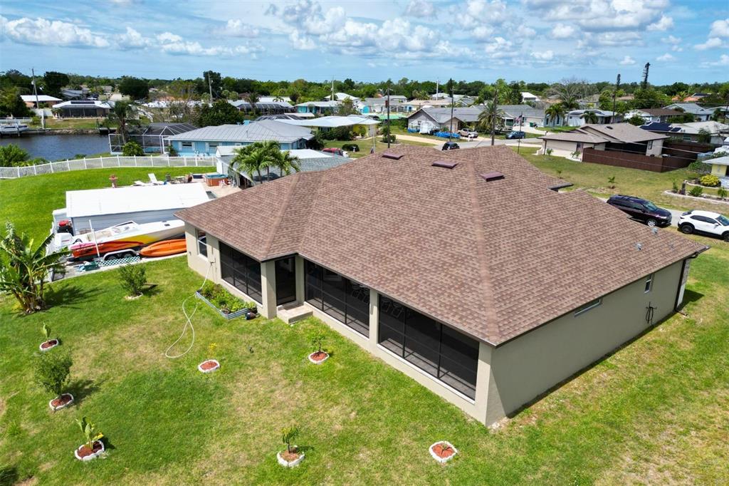 An aerial view of a house with a brown shingled roof and a screened-in porch — 729 CRESTVIEW CIRCLE NW, PORT CHARLOTTE, FL