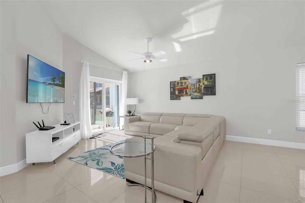A living room features a beige sectional sofa, a white media console, and tile flooring — 156 BAREFOOT BEACH WAY, KISSIMMEE, FL