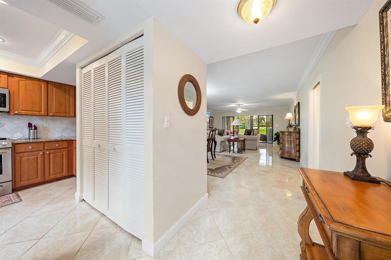 A view from a tiled hallway looking into a kitchen and an open living area — 803 Clubhouse Circle, Jupiter FL 33477, JUPITER, FL