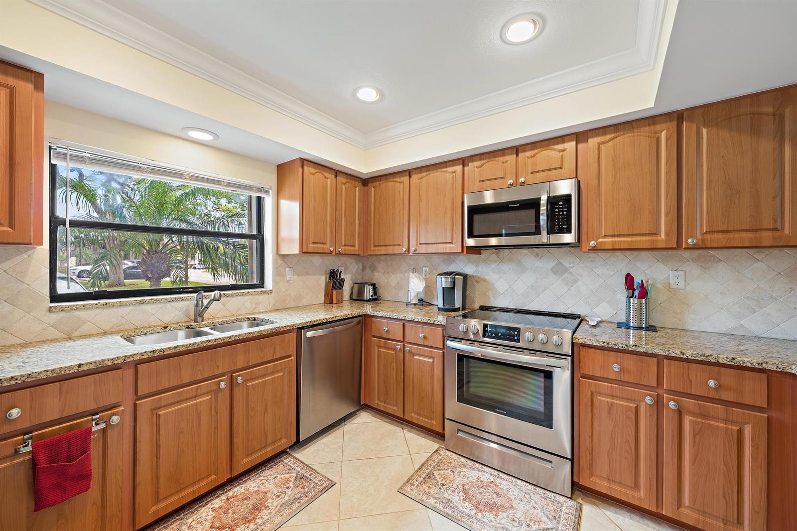 A kitchen with wood cabinets, granite countertops, stainless steel appliances, and a window over the sink — 803 Clubhouse Circle, Jupiter FL 33477, JUPITER, FL