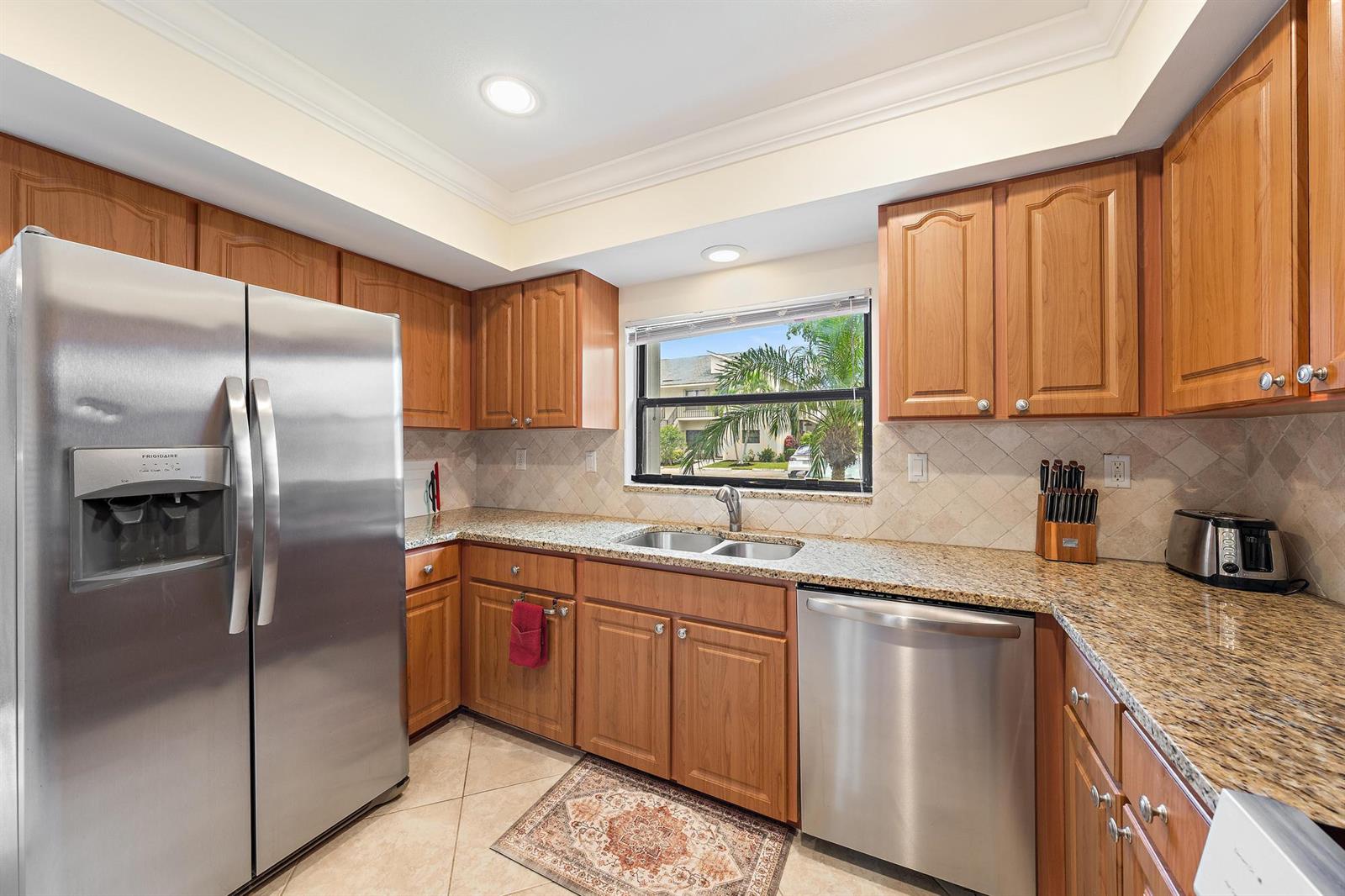 A kitchen with wood cabinets, granite countertops, stainless steel appliances, and a window over the sink — 803 Clubhouse Circle, Jupiter FL 33477, JUPITER, FL