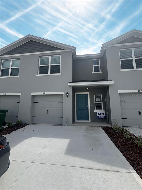 The exterior of a two-story gray townhouse features a blue front door and garage doors — 4615 LINDA DRIVE, LAKE WALES, FL