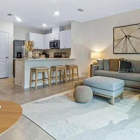 An open-concept kitchen with a breakfast bar overlooks a living room featuring a gray sofa — 4615 LINDA DRIVE, LAKE WALES, FL