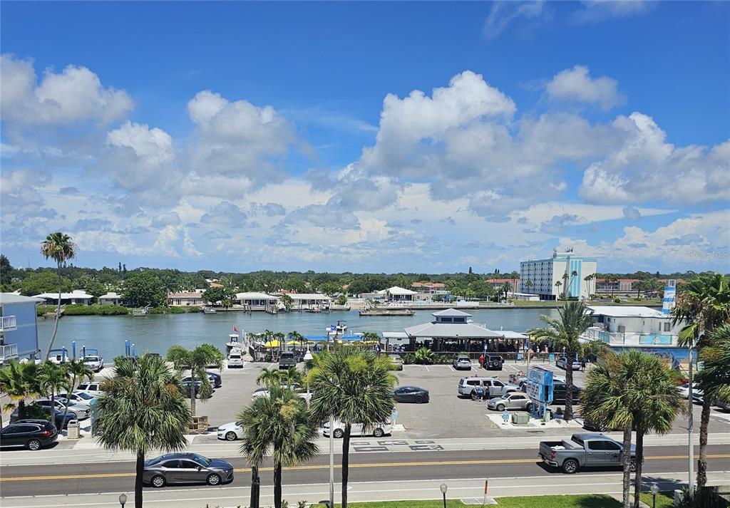 An elevated view of a parking lot, a waterway, and coastal buildings under a cloudy sky — 20040 GULF BOULEVARD UNIT 402, INDIAN ROCKS BEACH, FL