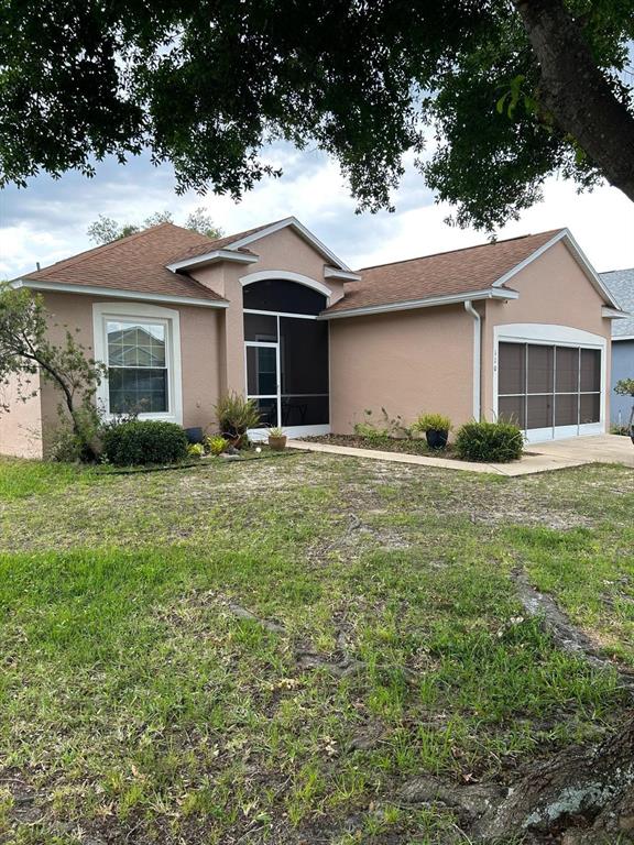 A single-story tan house features a screened front entryway and a two-car garage — 110 KNOLLWOOD DRIVE, DAVENPORT, FL