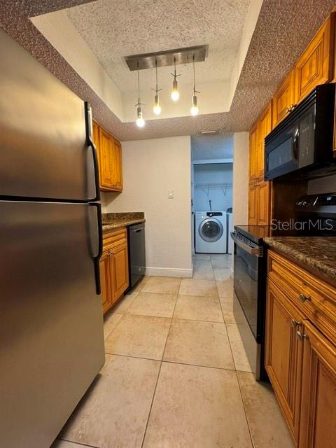 A kitchen with stainless steel appliances, wood cabinets, and a laundry area in the back — 4735 S TEXAS AVENUE UNIT 4735C, ORLANDO, FL