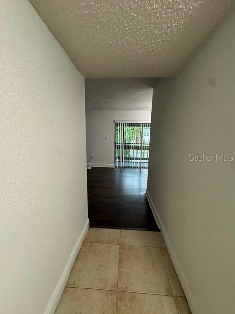 A tiled entryway leads into a living area with dark wood flooring and sliding doors — 4735 S TEXAS AVENUE UNIT 4735C, ORLANDO, FL