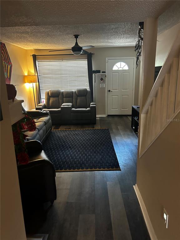 A living room features dark wood-look flooring, a gray sofa, and a staircase — 2118 FLETCHERS POINT CIRCLE, TAMPA, FL