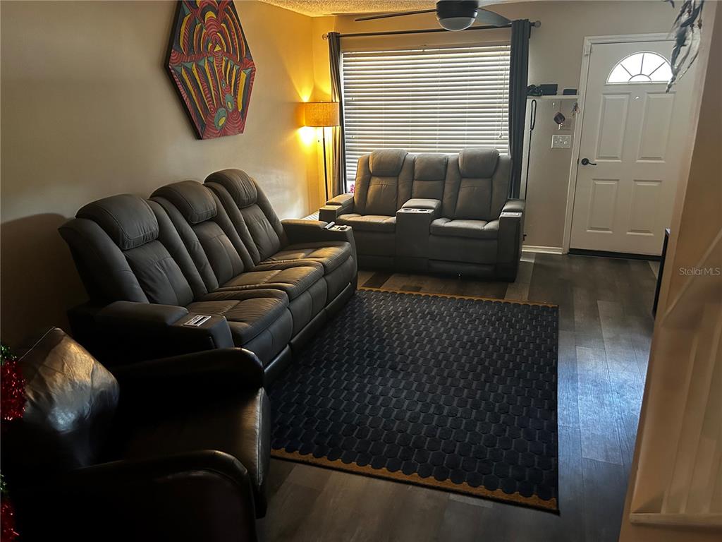 A living room features gray leather reclining furniture, a dark patterned rug, and wood-look flooring — 2118 FLETCHERS POINT CIRCLE, TAMPA, FL