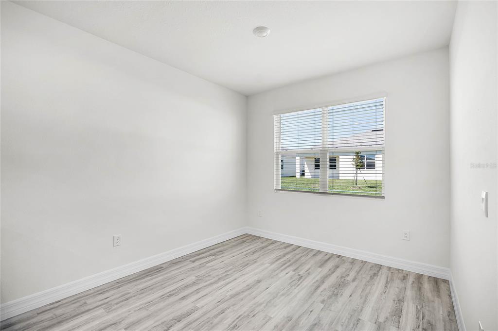 An empty room with white walls, light wood-look flooring, and a window with blinds — 5415 CLOUDBERRY AVENUE, LAKELAND, FL