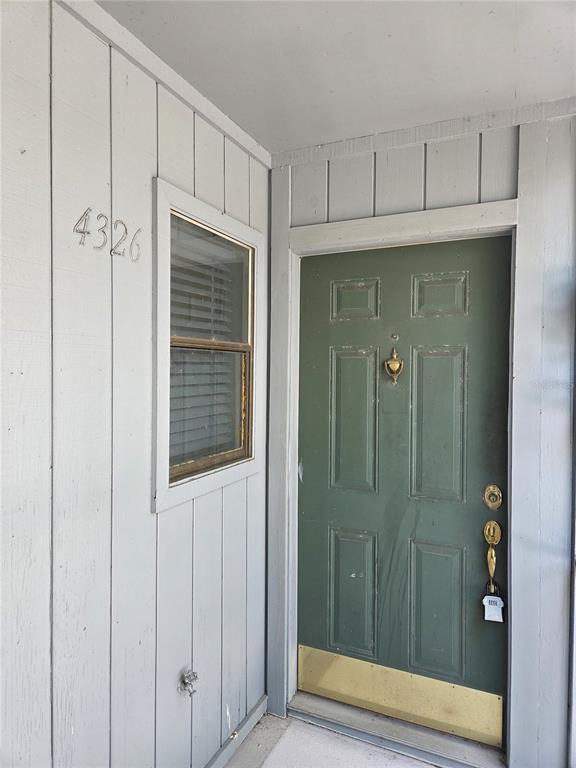 A green front door with a brass kickplate sits next to a window on a porch — 4326 AQUA VISTA DRIVE UNIT 10E, ORLANDO, FL