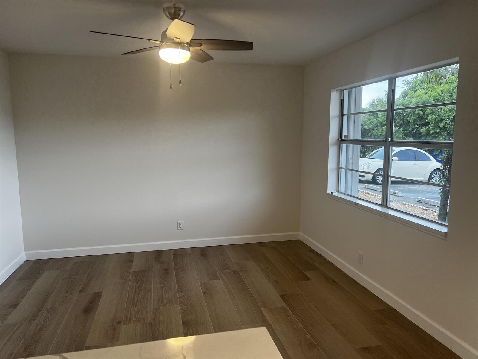 An empty room with light-colored walls, wood-look flooring, a ceiling fan, and a large window — 609 NE 6th Court # B, Boynton Beach FL 33435, BOYNTON BEACH, FL