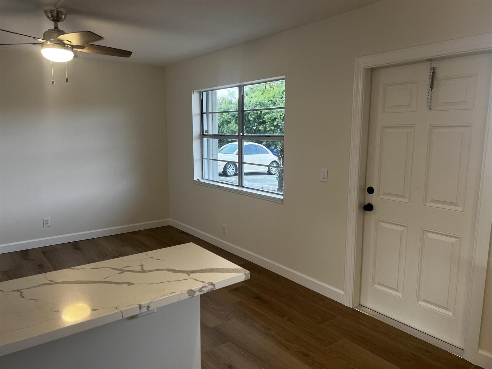 A room with wood-look flooring, a marble-topped island, a ceiling fan, and an exterior door — 609 NE 6th Court # B, Boynton Beach FL 33435, BOYNTON BEACH, FL