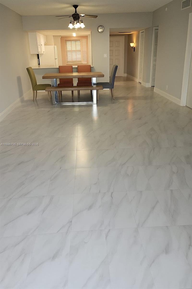 A dining area features a wooden table with a bench and chairs on marble-look tile — 2900 N Course Dr # 107, Pompano Beach FL 33069, POMPANO BEACH, FL