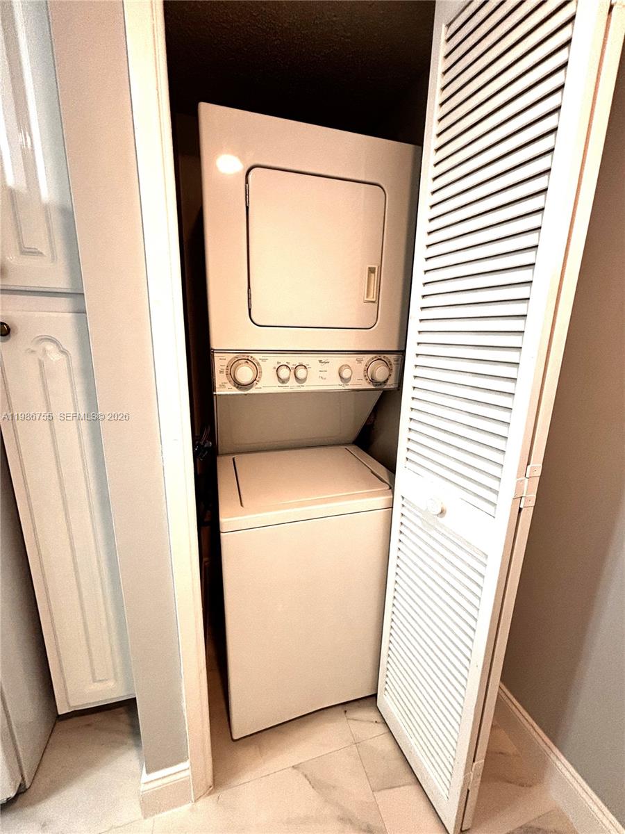 A white stacked washer and dryer unit is installed inside a small closet — 2900 N Course Dr # 107, Pompano Beach FL 33069, POMPANO BEACH, FL