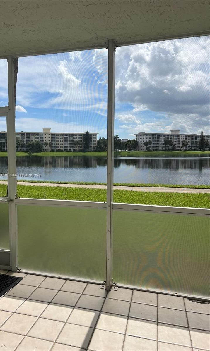 A screened-in balcony overlooks a lake and apartment buildings under a cloudy sky — 2900 N Course Dr # 107, Pompano Beach FL 33069, POMPANO BEACH, FL