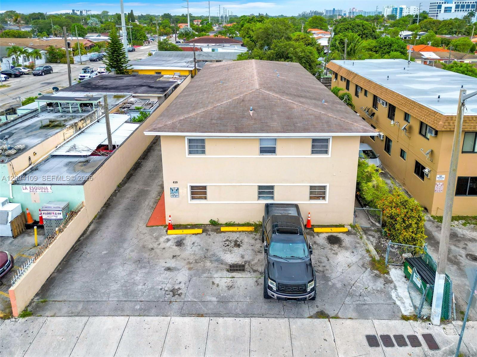 An aerial view shows a two-story tan apartment building with a parking lot in front — 410 NW 47th Ave, Miami FL 33126, MIAMI, FL