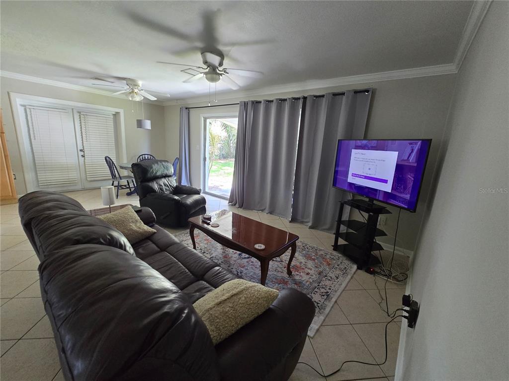 A living room features tile flooring, a leather sofa, a television, and sliding glass doors — 2456 EDNOR STREET, PORT CHARLOTTE, FL