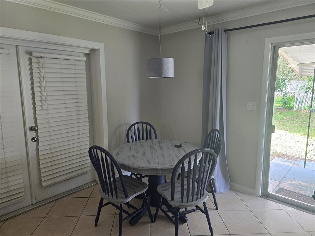 A dining area features a round table with four chairs, tile flooring, and sliding glass doors — 2456 EDNOR STREET, PORT CHARLOTTE, FL