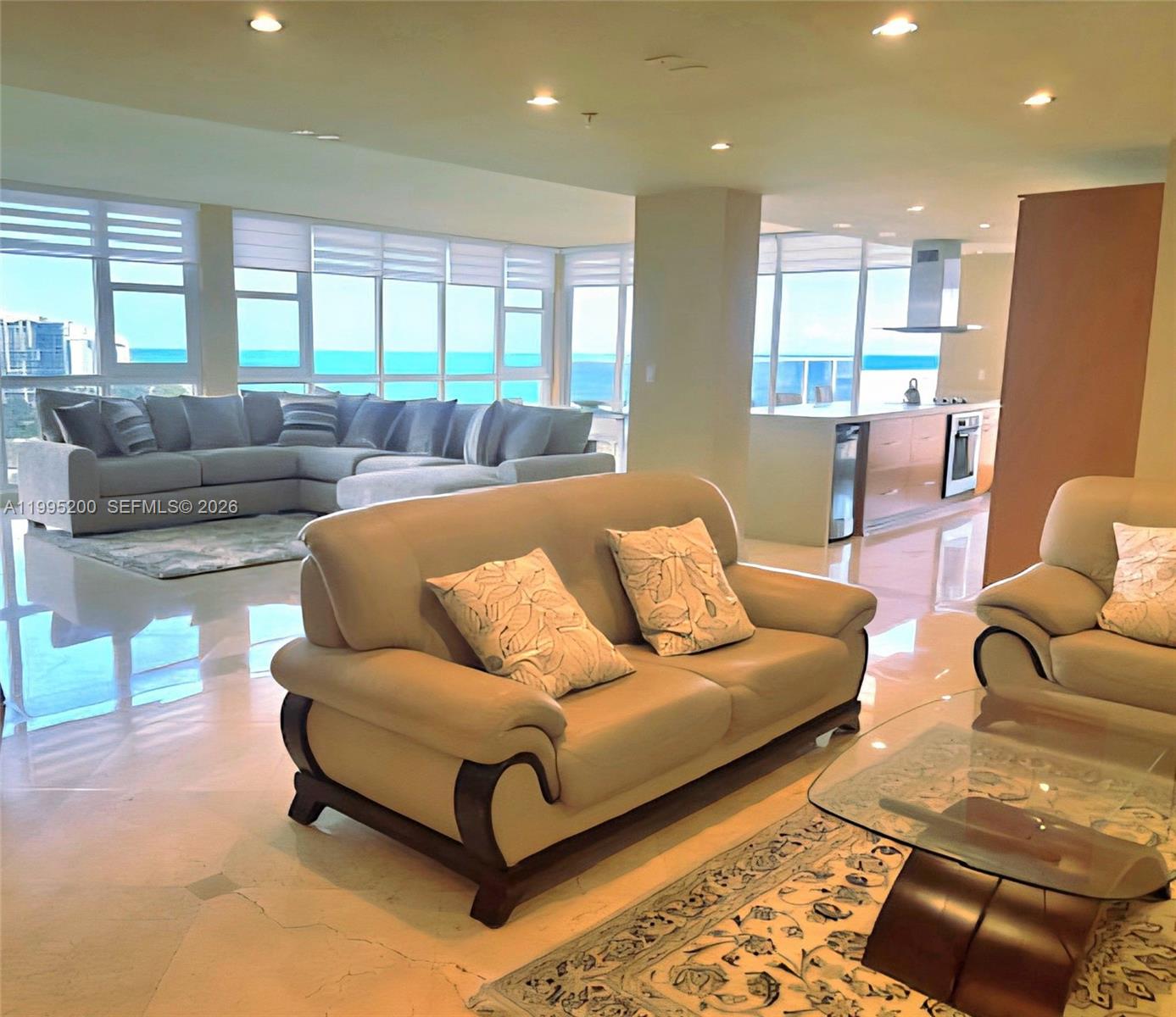 A spacious living room features a beige leather sofa, tile floors, and ocean views — 100 Lincoln Rd, Miami Beach FL 33139, MIAMI BEACH, FL
