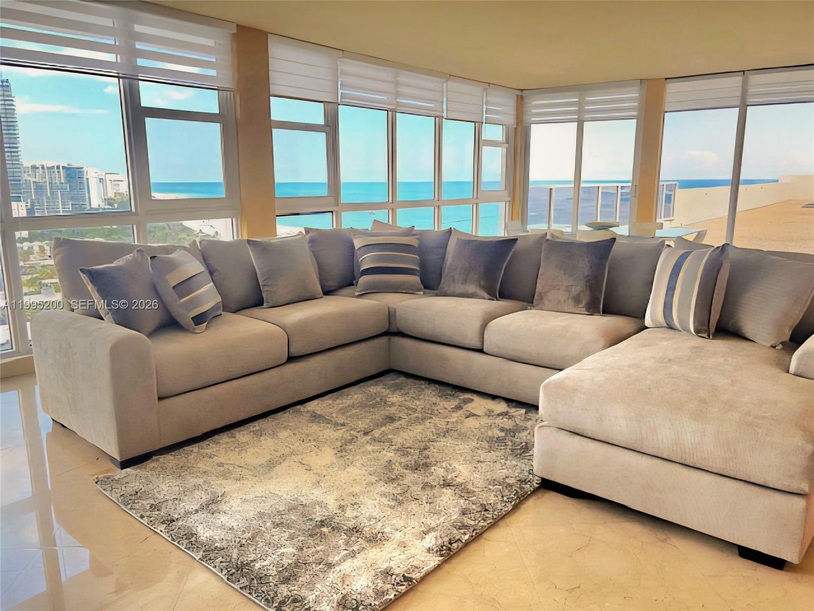 A living room features a large sectional sofa, a patterned rug, and floor-to-ceiling ocean views — 100 Lincoln Rd, Miami Beach FL 33139, MIAMI BEACH, FL