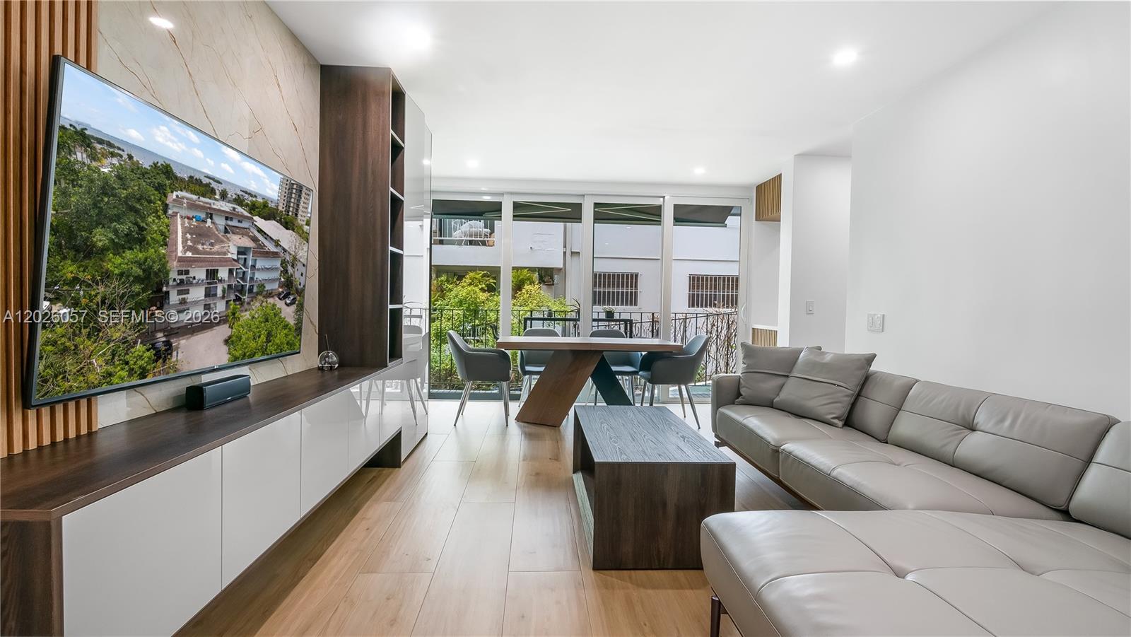 A modern living room features a large television, leather sectional, and dining area with balcony — 2539 S Bayshore Dr # 212A, Miami FL 33133, MIAMI, FL