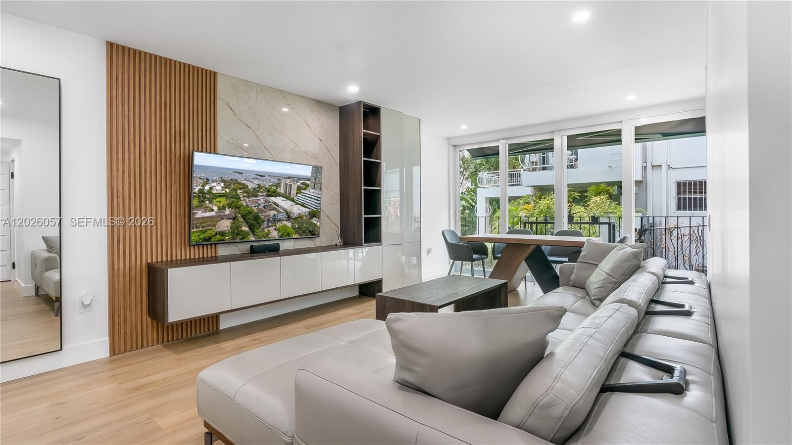 A modern living room features a wood-slatted accent wall, a floating media console, and a sectional — 2539 S Bayshore Dr # 212A, Miami FL 33133, MIAMI, FL