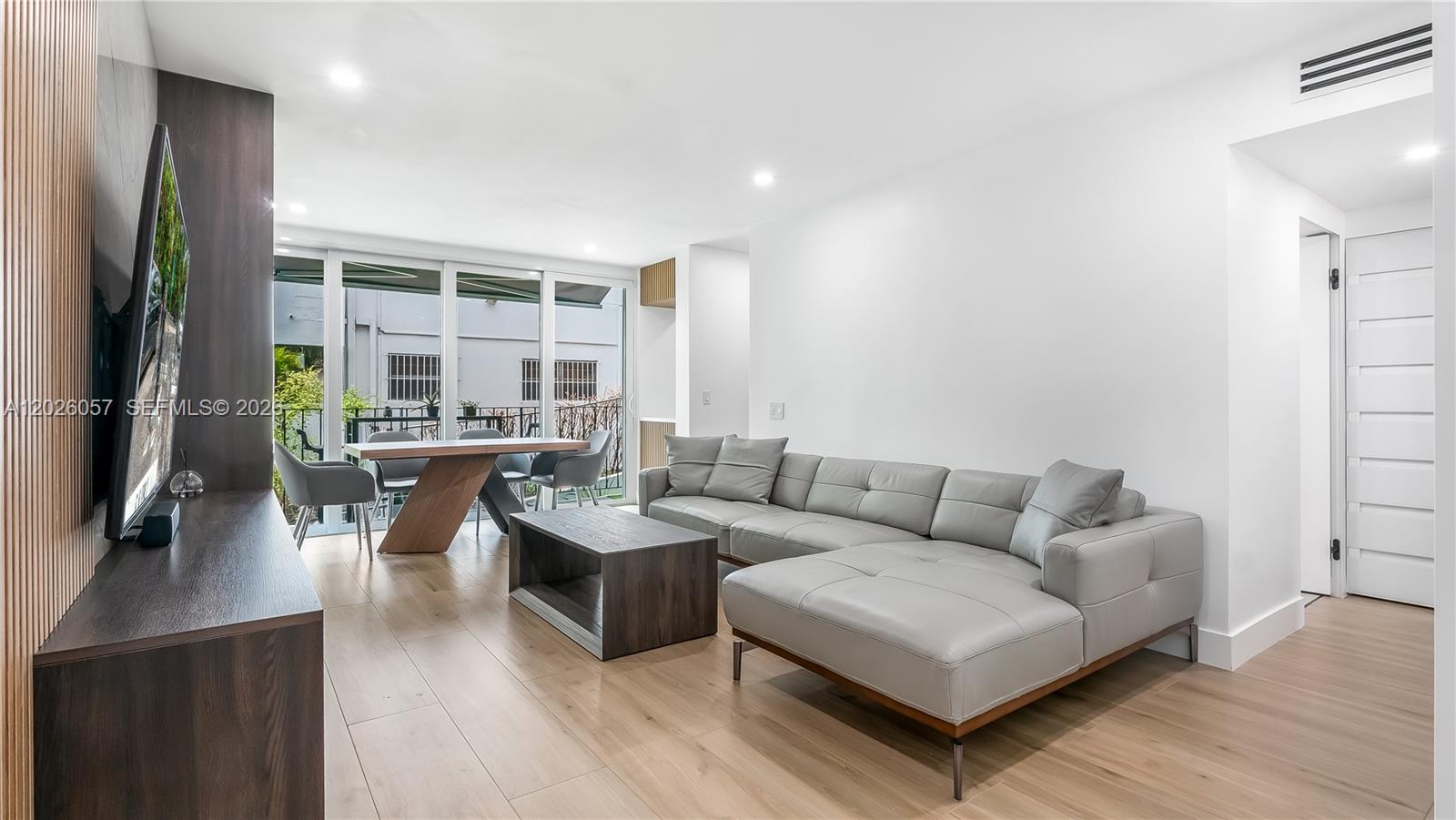 A modern living room features a grey sectional sofa, wooden coffee table, and dining area — 2539 S Bayshore Dr # 212A, Miami FL 33133, MIAMI, FL