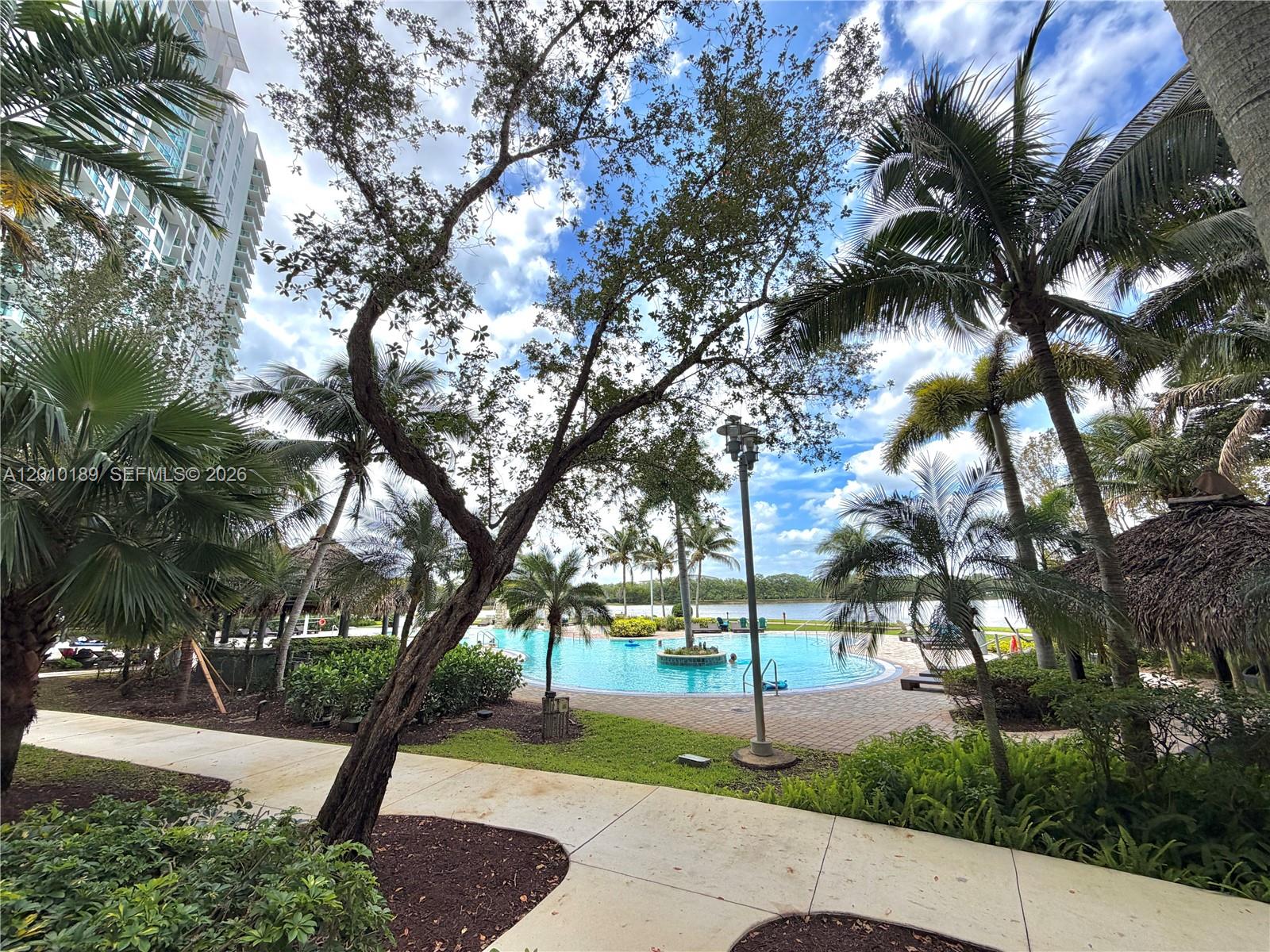 A swimming pool sits near a walkway surrounded by palm trees and a tall building — 2641 N Flamingo Rd, Sunrise FL 33323, SUNRISE, FL